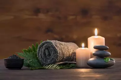 A towel, stones and candles sit on a table .