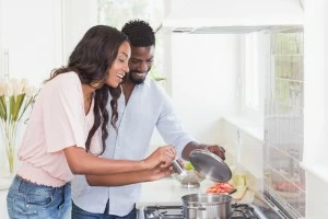 A happy couple cooking together in the kitchen.