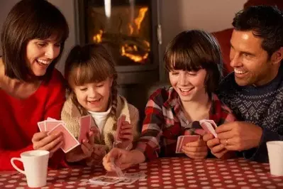 Family playing card games by the fireplace